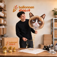 Jesse houdt de Grumpy Cat Helium Ballon vast in de warme inpakruimte van Ballonnenshop.nl.
