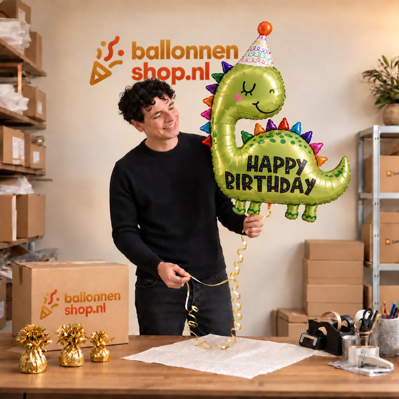Jesse houdt de Happy Birthday Dino XL Ballon vast in de warme inpakruimte van Ballonnenshop.nl.