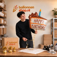 Jesse houdt de Happy Birthday Taart XL Ballon vast in de warme inpakruimte van Ballonnenshop.nl.