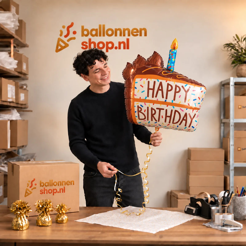 Jesse houdt de Happy Birthday Taart XL Ballon vast in de warme inpakruimte van Ballonnenshop.nl.