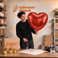 Jesse houdt de Mega Rood Hart helium ballon vast in de warme inpakruimte van Ballonnenshop.nl.