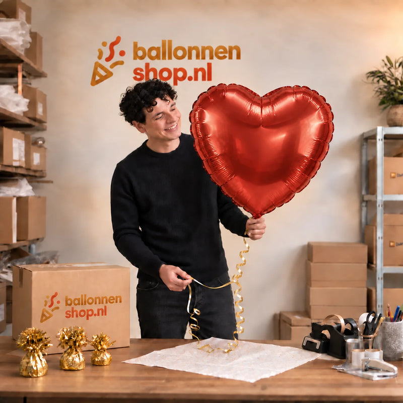 Jesse houdt de Mega Rood Hart helium ballon vast in de warme inpakruimte van Ballonnenshop.nl.