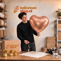 Jesse houdt de Hart Ballon Rose Goud – 61 cm vast in de warme inpakruimte van Ballonnenshop.nl.