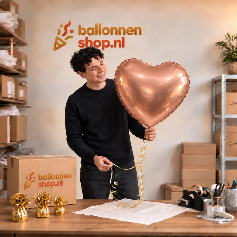 Jesse houdt de Hart Ballon Rose Goud – 61 cm vast in de warme inpakruimte van Ballonnenshop.nl.