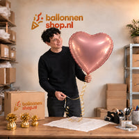 Jesse houdt de Hart Ballon Roze – 61 cm vast in de warme inpakruimte van Ballonnenshop.nl.