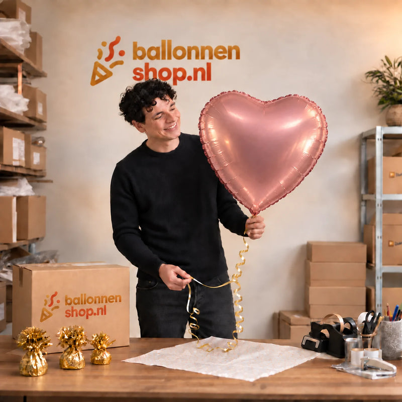 Jesse houdt de Hart Ballon Roze – 61 cm vast in de warme inpakruimte van Ballonnenshop.nl.