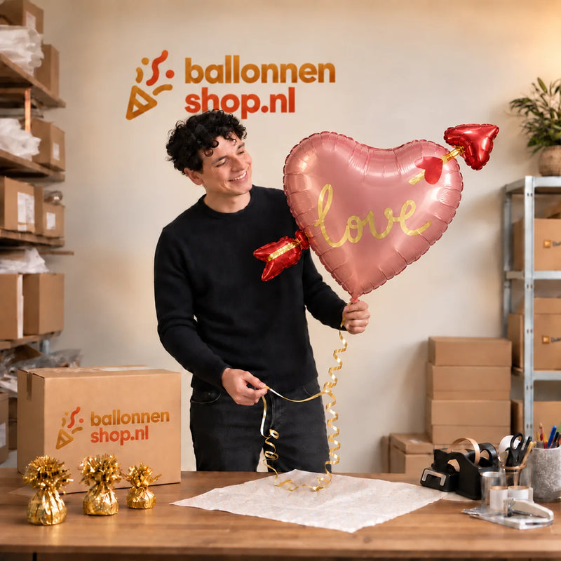 Jesse houdt de Hart Met Pijl Helium XL Ballon vast in de warme inpakruimte van Ballonnenshop.nl.
