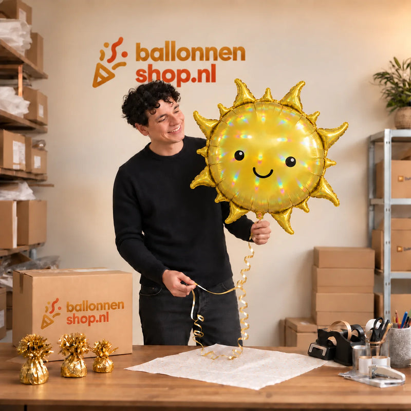 Jesse houdt de Holografische Zon Helium Ballon vast in de warme inpakruimte van Ballonnenshop.nl.