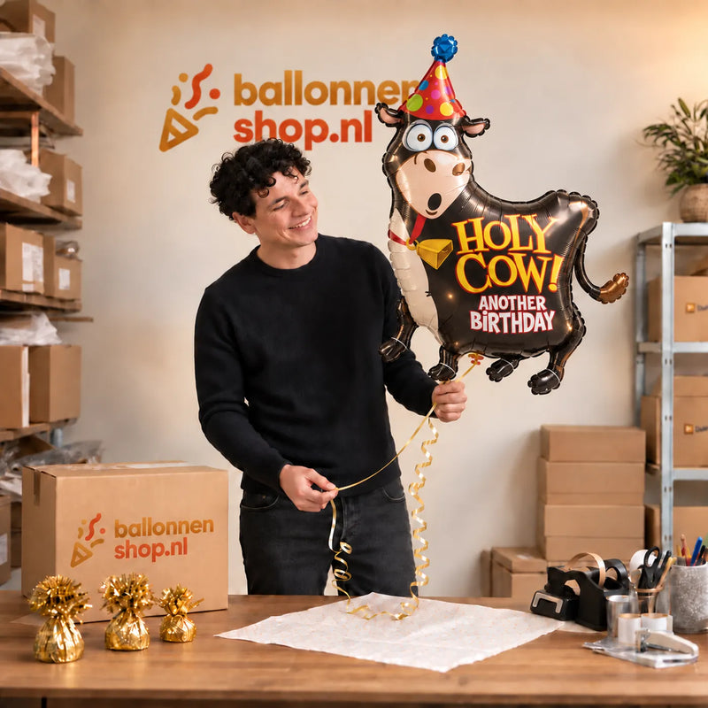 Jesse houdt de Holy Cow Birthday XL Ballon vast in de warme inpakruimte van Ballonnenshop.nl.