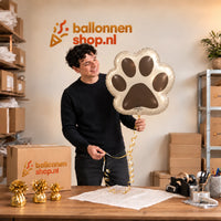 Jesse houdt de Hondenpoot Helium Ballon vast in de warme inpakruimte van Ballonnenshop.nl.