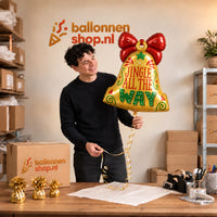 Jesse houdt de Jingle All The Way Bel Ballon vast in de warme inpakruimte van Ballonnenshop.nl.