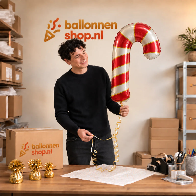 Jesse houdt de Kerst Zuurstok Helium XL Ballon vast in de warme inpakruimte van Ballonnenshop.nl.