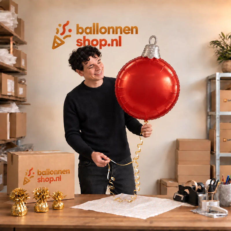 Jesse houdt de Kerstbal 4D Helium Ballon vast in de warme inpakruimte van Ballonnenshop.nl.