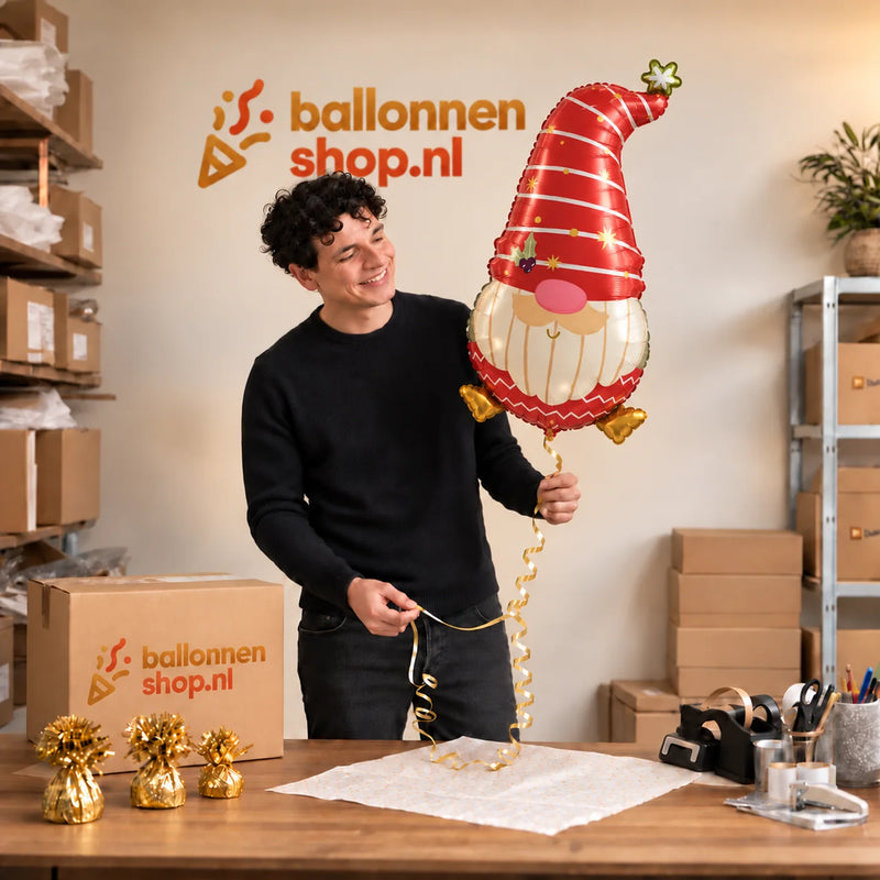 Jesse houdt de Kerstkabouter Helium Ballon vast in de warme inpakruimte van Ballonnenshop.nl.