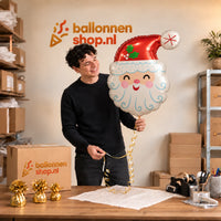 Jesse houdt de Kerstman Helium Ballon vast in de warme inpakruimte van Ballonnenshop.nl.