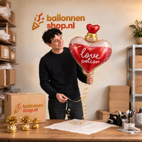 Jesse houdt de Liefdesdrankje Helium Ballon vast in de warme inpakruimte van Ballonnenshop.nl.