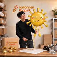 Jesse houdt de Lopende Zon Helium XL Ballon vast in de warme inpakruimte van Ballonnenshop.nl.