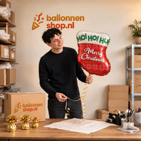 Jesse houdt de Merry Christmas Sok + Kerstboom vast in de warme inpakruimte van Ballonnenshop.nl.