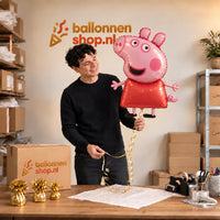 Jesse houdt de Peppa Pig Helium XL Ballon vast in de warme inpakruimte van Ballonnenshop.nl.