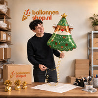 Jesse houdt de Rendier In Kerstboom Ballon vast in de warme inpakruimte van Ballonnenshop.nl.