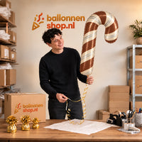 Jesse houdt de Satijnchocolade Kerst Zuurstok XL vast in de warme inpakruimte van Ballonnenshop.nl.