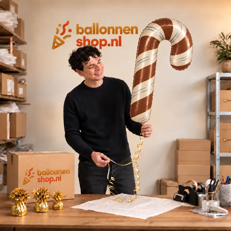Jesse houdt de Satijnchocolade Kerst Zuurstok XL vast in de warme inpakruimte van Ballonnenshop.nl.