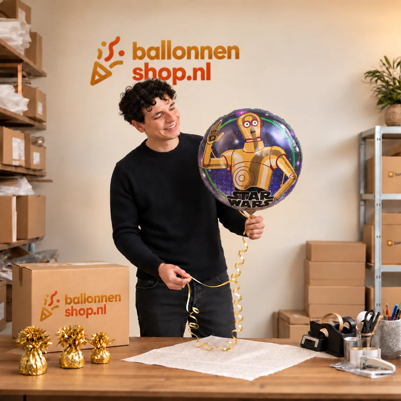 Jesse houdt de Star Wars C3PO Helium Ballon vast in de warme inpakruimte van Ballonnenshop.nl.