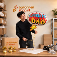 Jesse houdt de Superhero Dad Helium Ballon vast in de warme inpakruimte van Ballonnenshop.nl.