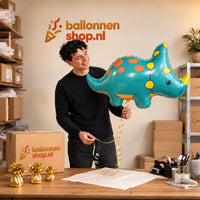 Jesse houdt de Triceratops Dino Helium XL Ballon vast in de warme inpakruimte van Ballonnenshop.nl.