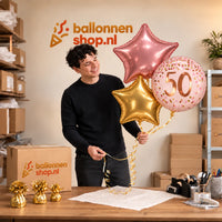 Jesse houdt het 50 Jaar Trosje Roze/Goud/Rose Goud vast in de warme werkplaats van Ballonnenshop.nl.