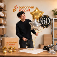 Jesse houdt 60 Jaar Trosje Zilver/Zwart/Goud vast in de warme werkplaats van Ballonnenshop.nl.