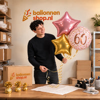 Jesse houdt 60 Jaar Trosje Roze/Goud/Rose Goud vast in de warme werkplaats van Ballonnenshop.nl.