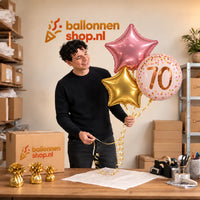 Jesse houdt 70 Jaar Trosje Roze/Goud/Rose Goud vast in de warme werkplaats van Ballonnenshop.nl.