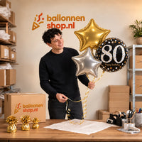Jesse houdt 80 Jaar Trosje Zilver/Zwart/Goud vast in de warme werkplaats van Ballonnenshop.nl.