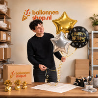 Jesse houdt Happy Birthday Trosje Zilver/Zwart/Goud vast in de warme werkplaats van Ballonnenshop.nl.