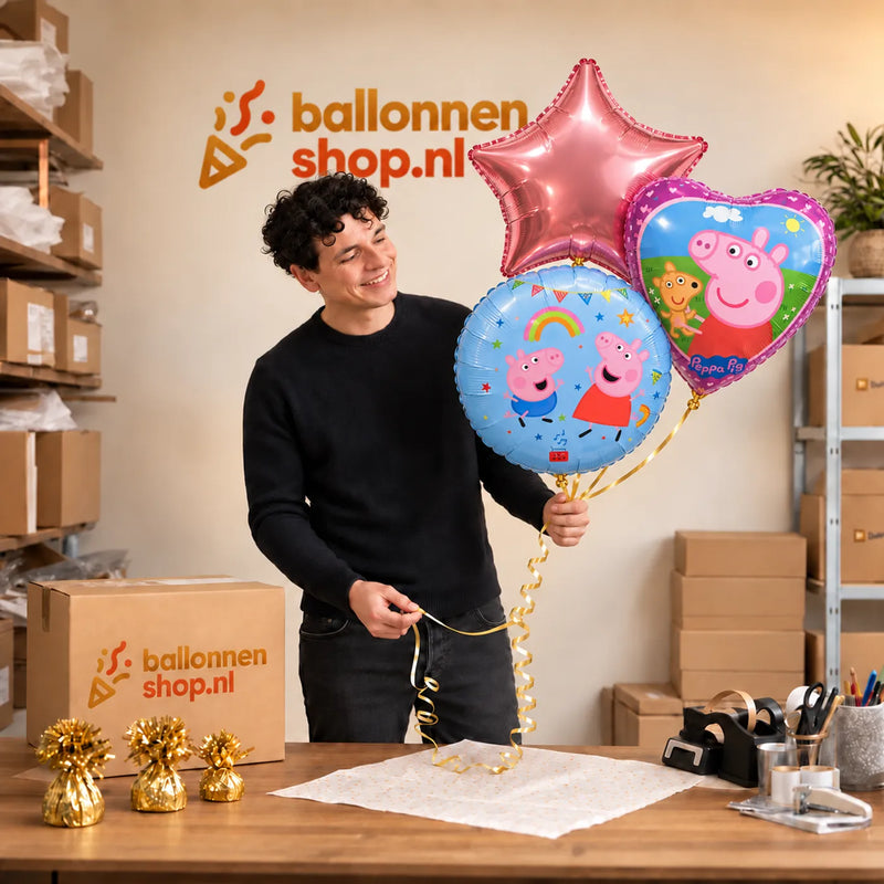 Jesse houdt Peppa Pig Trosje Paars/Roze/Blauw vast in de warme werkplaats van Ballonnenshop.nl.