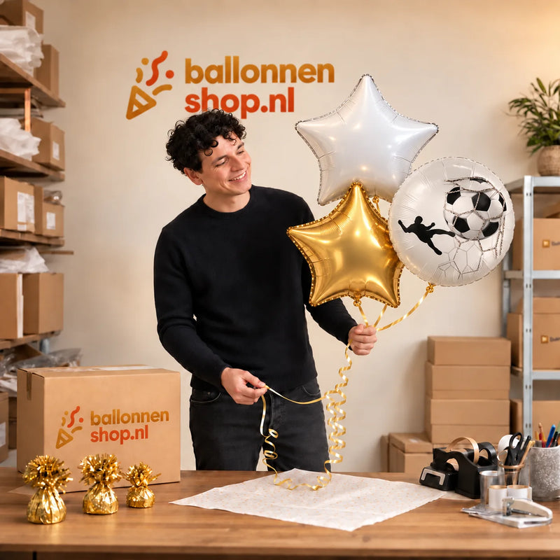 Jesse houdt Voetbal Trosje Goud/Wit/Zwart vast in de warme werkplaats van Ballonnenshop.nl.