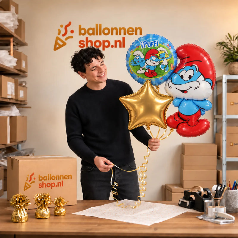Jesse houdt Smurfen Trosje blauw/wit/groen/rood vast in de warme werkplaats van Ballonnenshop.nl.