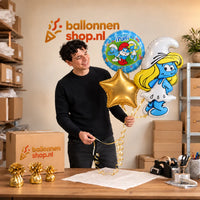 Jesse houdt Smurfen Trosje blauw/wit/groen/geel vast in de warme werkplaats van Ballonnenshop.nl.