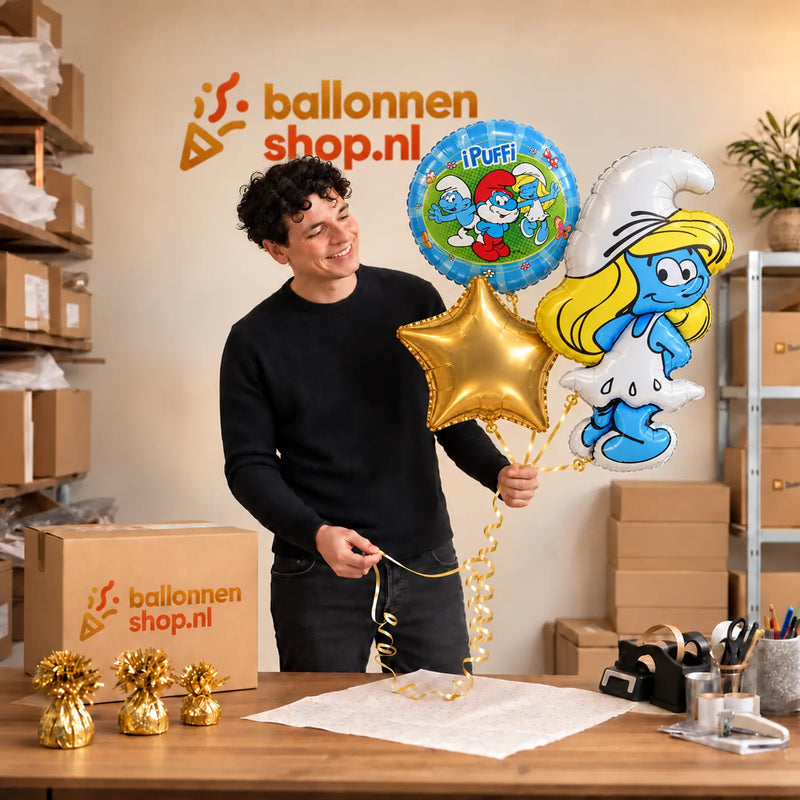 Jesse houdt Smurfen Trosje blauw/wit/groen/geel vast in de warme werkplaats van Ballonnenshop.nl.