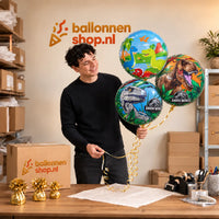 Jesse houdt Dinosaurus Trosje Blauw/Groen/Rood vast in de warme werkplaats van Ballonnenshop.nl.