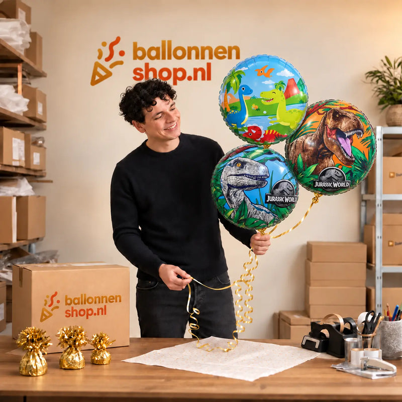Jesse houdt Dinosaurus Trosje Blauw/Groen/Rood vast in de warme werkplaats van Ballonnenshop.nl.