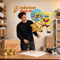 Jesse houdt Spongebob Trosje Goud/Blauw/Geel – 71 cm vast in de warme werkplaats van Ballonnenshop.nl.