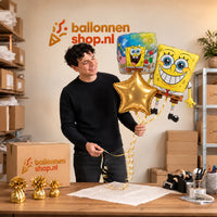 Jesse houdt Spongebob Trosje Goud/Blauw/Geel – 64 cm vast in de warme werkplaats van Ballonnenshop.nl.