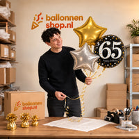 Jesse houdt 65 Jaar Trosje Zilver/Zwart/Goud vast in de warme werkplaats van Ballonnenshop.nl.