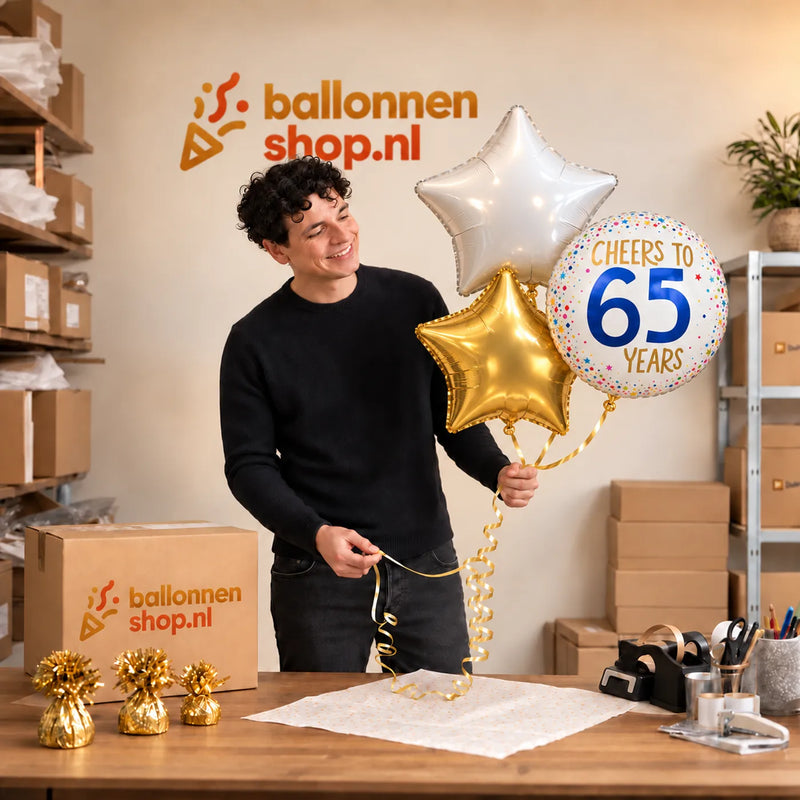 Jesse houdt 65 Jaar Trosje Wit/Goud/Blauw vast in de warme werkplaats van Ballonnenshop.nl.