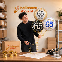 Jesse houdt 65 Jaar Trosje Zwart/Goud/Zilver/Blauw vast in de warme werkplaats van Ballonnenshop.nl.