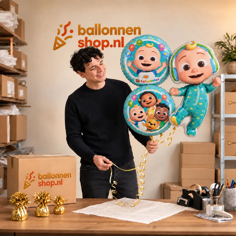 Jesse houdt Cocomelon Trosje Blauw/Wit/Groen – 76 cm vast in de warme werkplaats van Ballonnenshop.nl.