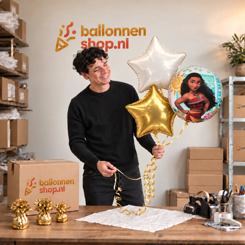 Jesse houdt Vaiana Trosje Blauw/Wit/Goud vast in de warme werkplaats van Ballonnenshop.nl.