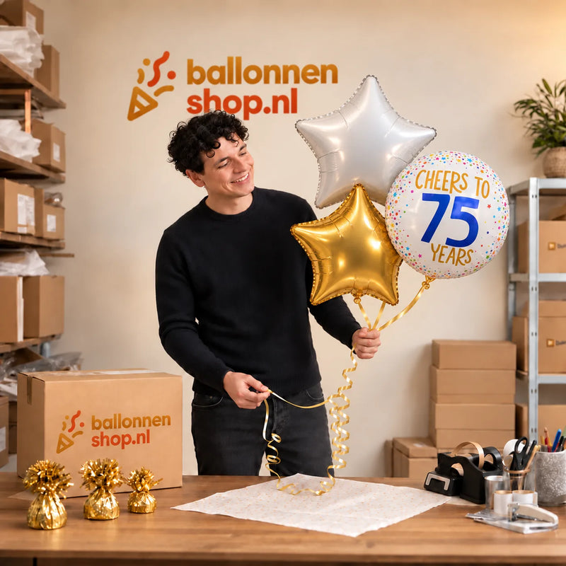 Jesse houdt 75 Jaar Trosje Wit/Goud/Blauw vast in de warme werkplaats van Ballonnenshop.nl.